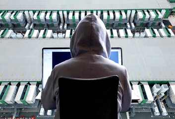 Close-up of a hacker behind a laptop and a large datacenter in the background