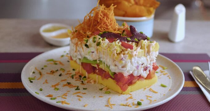 Closeup of well-served Peruvian Causa on white plate in a restaurant, with blurred background