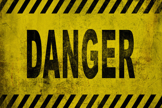 WARNING danger sign word text as stencil with yellow and black stripes painted over concrete wall cement texture wide banner background. Concept image for caution, dangerous area and hazard.
