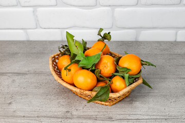 tangerines with leaves in a basket on the kitchen table