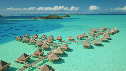 Obraz premium Aerial view luxury resort with overwater bungalows in crystal clear turquoise water, creating an idyllic tropical paradise scene. Maldives remote wild nature paradise, exotic summer luxury travel