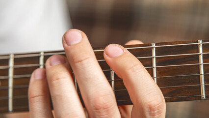 Man's hands playing electric guitar, close up at home