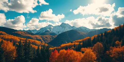 Autumnal mountain landscape with vibrant foliage and snow-capped peaks under a partly cloudy sky