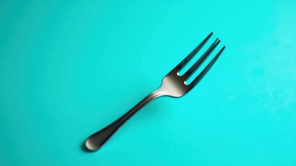 Fototapeta premium Single metal fork on a vibrant teal background