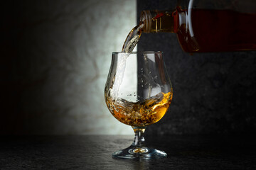 Pouring brandy from a bottle into a glass.