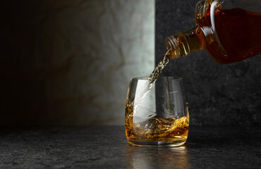 Pouring whiskey from a bottle into a glass.