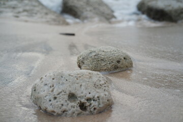 A smooth stone rests on the sandy beach