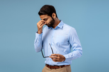 Stressed Indian businessman holding head, eyes closed, showing pain and exhaustion