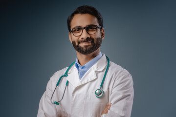 Happy, handsome, attractive Indian man, doctor wearing white coat, stethoscope with crossed arms