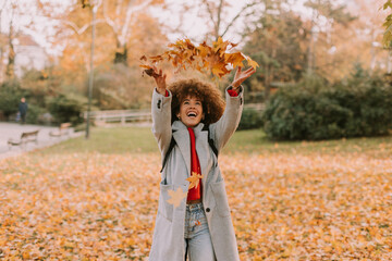 Joyful celebration of autumn with colorful leaves dancing in the air in a serene park setting