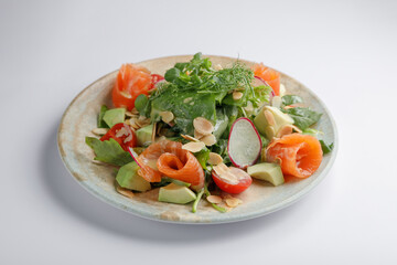 A plate of salad with avocado, tomatoes, and radishes