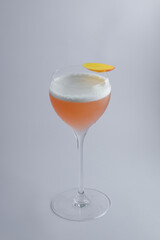 A crafted cocktail in a wine glass, topped with a slice of orange