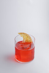 A beautiful glass filled with red liquid and a slice of orange on top