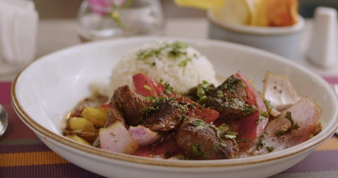 fresh, delicious Peruvian Sauteed Loin with rice in a white plate on table in a restaurant