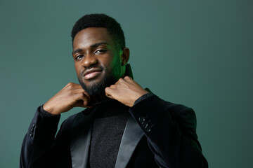 Confident african man in stylish black attire posing against vibrant green background