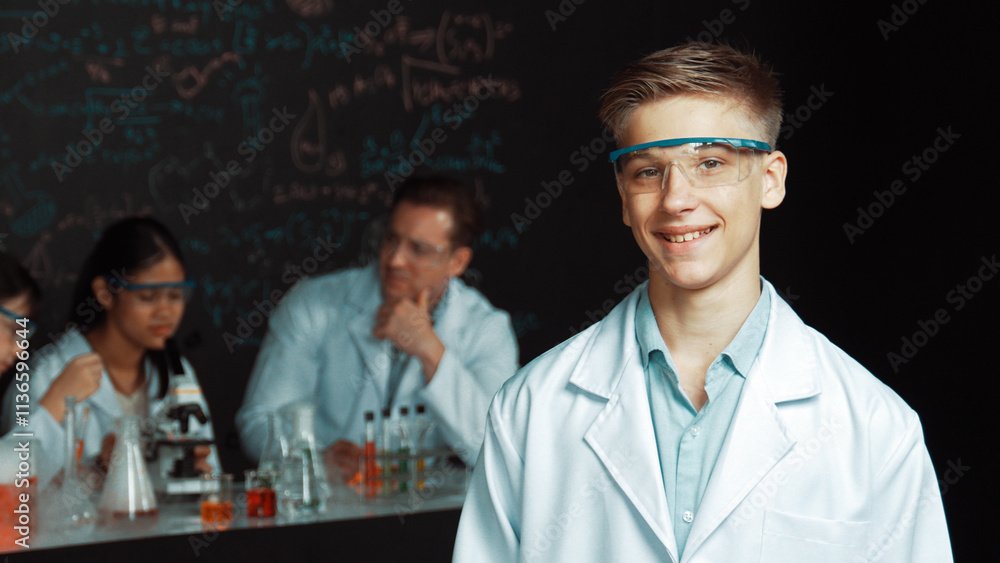 Aufkleber smart student looking at camera while diverse group doing experiment. attractive academic boy standi
