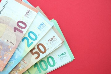 Big amount of one hundred, twenty, ten and fifty euro money bills on red background