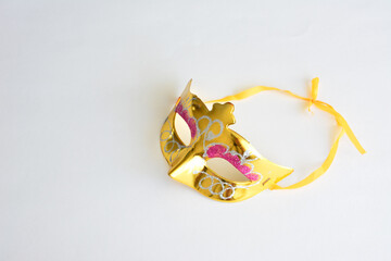 a golden mask with a pink and white decoration on it isolated on white