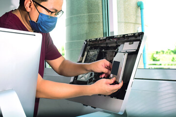 Computer technician wearing a mask and goggles Dismantling computer equipment for repairs, replacing parts and making repairs on his table