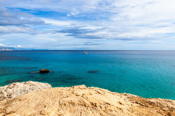 Fototapeta premium Sardinia. Italy. Crystal clear Mediterranean sea, beautiful rocks and white sailboat. Cala Goloritze, Baunei area, Sardinia, Italy.