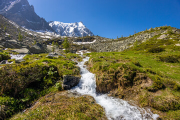 Alps scenic landscape on Tour du Montblanc. Rocky and snow summit peaks of the Alps on the trekking route TMB around Mont Blanc in Chamonix and Courmayeur. Alpine scene with mountains and lakes 