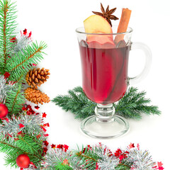 A glass of Christmas mulled wine in a frame of fir branches and New Year decorations.