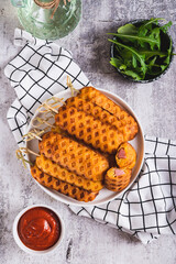 Grilled corn dogs with sausage on a plate and ketchup on the table top and vertical view