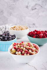 Assorted frozen red, white and black berries in bowls on table vertical view