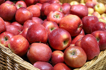 Red apples in a wicker basket. Fresh harvest, ripe fruits on in a supermarket