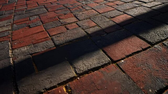 Camera zooms in on brick pavement video with deep red and gray tones in repeating patterns