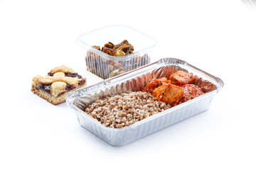 a white background disposable plastic and foil tableware airplane food snack boiled buckwheat with stewed vegetables healthy nutrition sweet cake