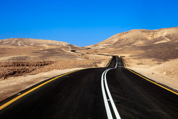The paved road loops through yellow lifeless sandy hills.  Excellent road quality and layout allows to maintain high speed of movement