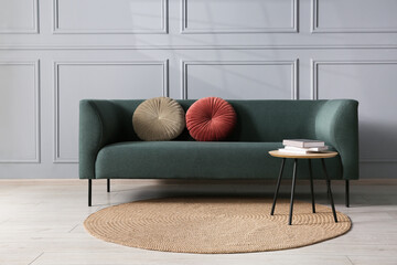 Comfortable sofa and side table near grey wall in room