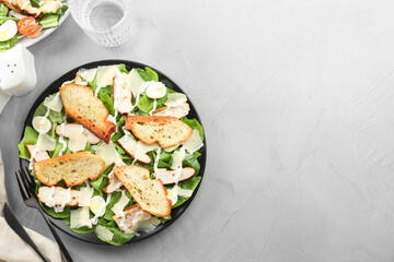 Delicious Caesar salad with chicken served on grey textured table, flat lay. Space for text