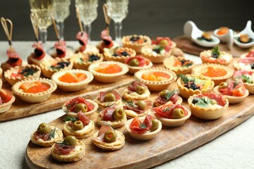 Many different tasty canapes and wine on white table