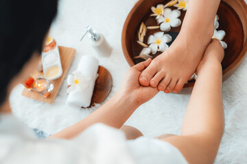Woman indulges in blissful foot massage at luxurious spa salon while masseur give reflexology therapy in gentle day light ambiance resort or hotel foot spa. Quiescent