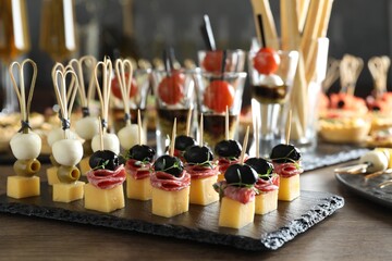 Many different tasty canapes on wooden table, closeup