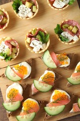 Many different tasty canapes on wooden table, flat lay