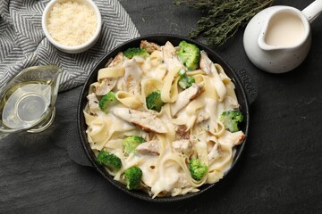 Delicious pasta Alfredo with chicken served on black table, flat lay