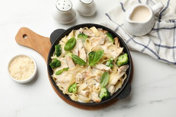Delicious pasta Alfredo with chicken served on white marble table, flat lay