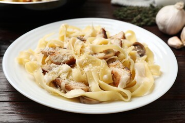 Tasty Alfredo pasta with chicken and mushrooms on wooden table, closeup
