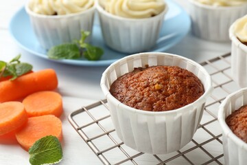 Delicious carrot muffins and fresh vegetable on white wooden table, closeup