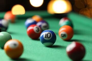 Many colorful billiard balls on green table indoors, closeup