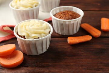 Delicious carrot muffins and fresh vegetables on wooden table, closeup