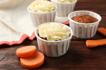 Delicious carrot muffins and fresh vegetables on wooden table, closeup