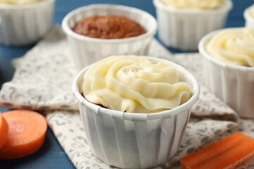 Delicious carrot muffins and fresh vegetables on blue table, closeup