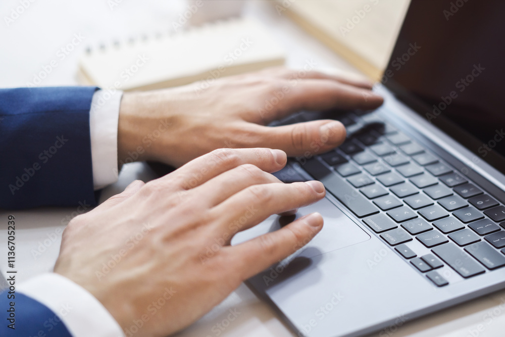 Poster The blurred office scene is the backdrop for a close-up view of a man's hands as they type on a modern laptop.
