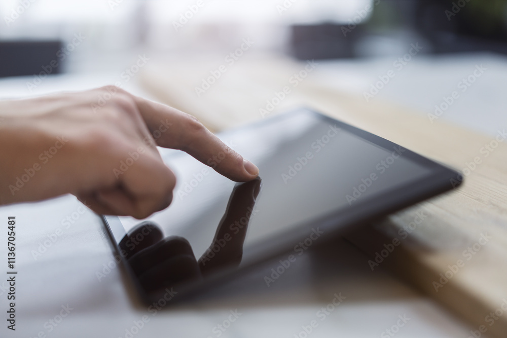 Aufkleber man's finger engaging with a cutting-edge digital tablet screen, device situated on a desk within th