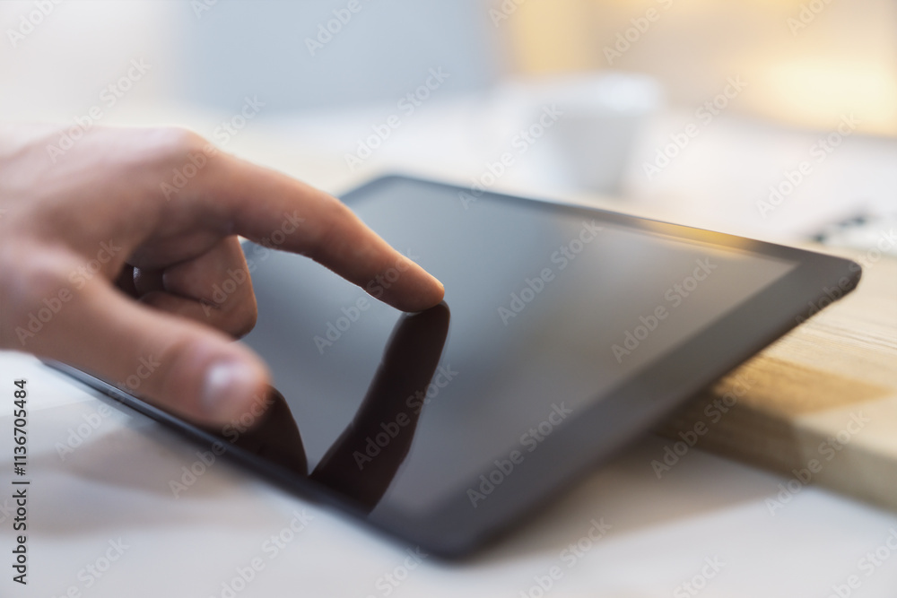 Poster close detail of a man's finger making contact with the screen of a sleek digital tablet resting on a