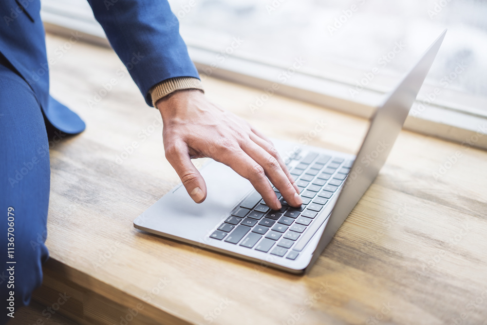 Poster set against a blurred office scene, the image reveals a close-up of a man's hands typing on a modern